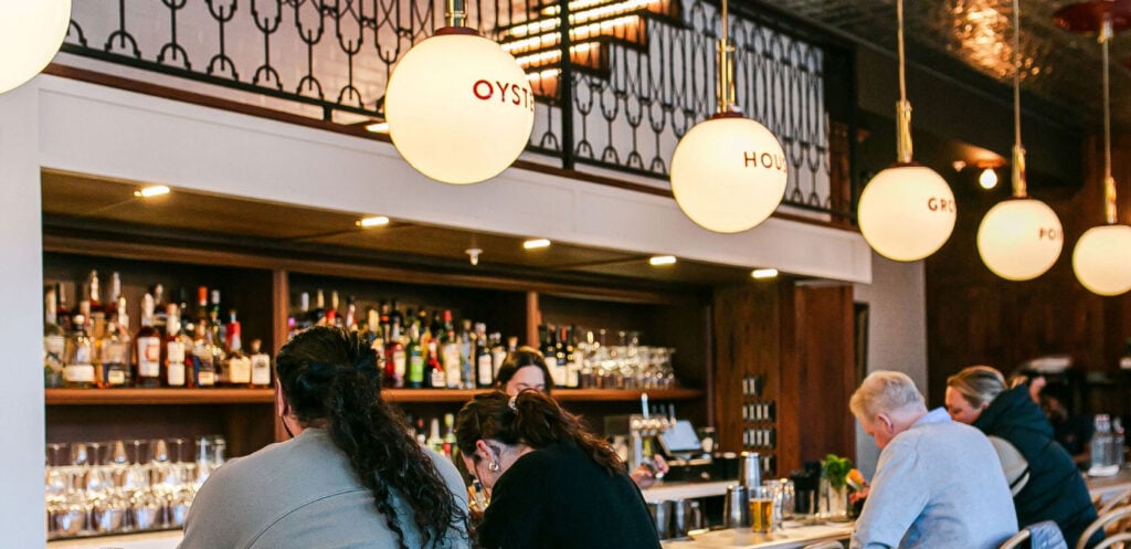Busy dining room and bar area with glowing oyster house pendant lights featured on the Brine Oyster House careers page