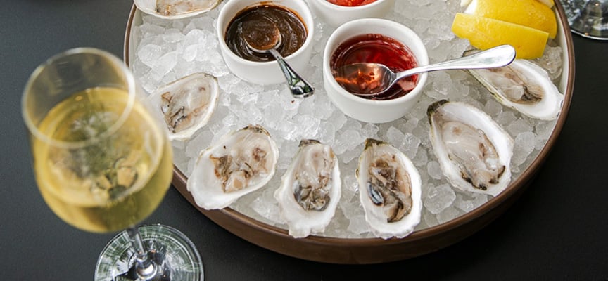 Fresh shucked oysters on ice with sauces and white wine during the Brine Oyster House happy hour